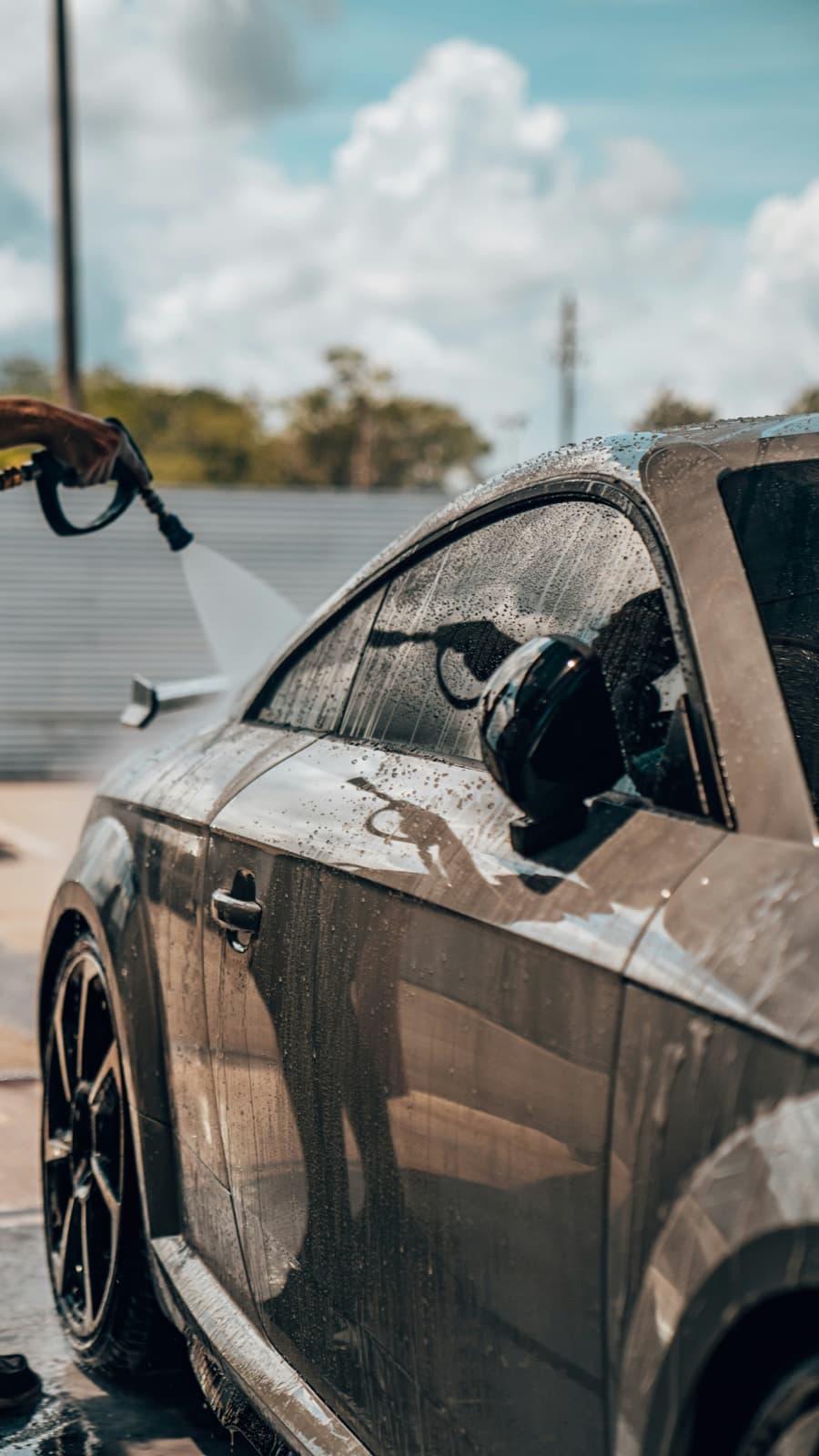 Person pressure washing the side window of a vehicle